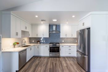 a kitchen with white cabinets and stainless steel appliances